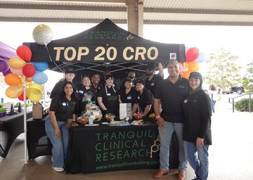 Tranquil Clinical Research staff pose in front of their tent at a community outreach event