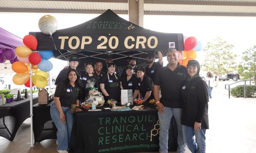 Tranquil Clinical Research staff pose in front of their tent at a community outreach event