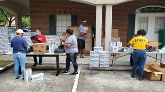 Five community members package up supplies after a natural disaster.